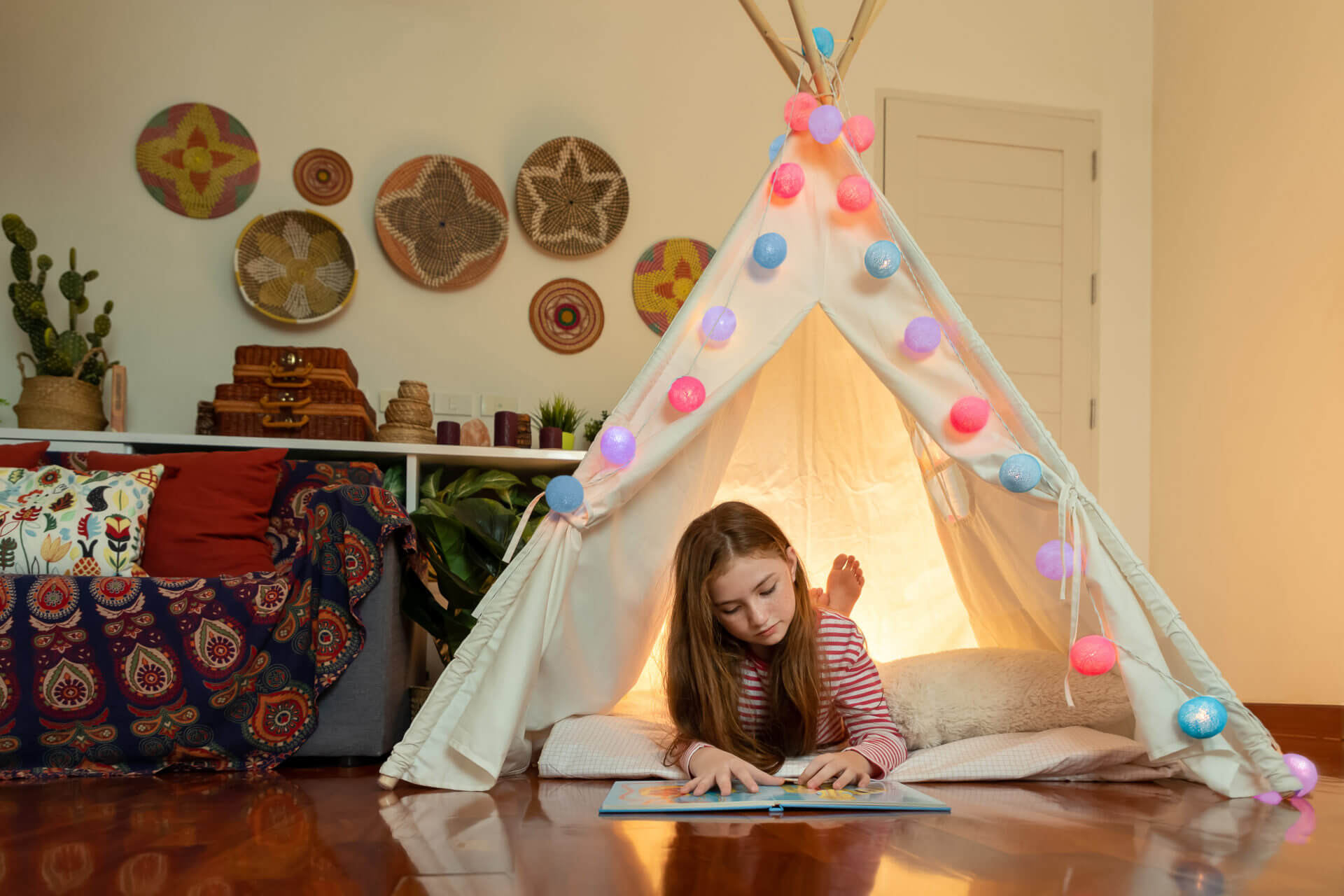 Attractive cute girl lying and reading book inside tepee tent in her bedroom enjoy happy time.