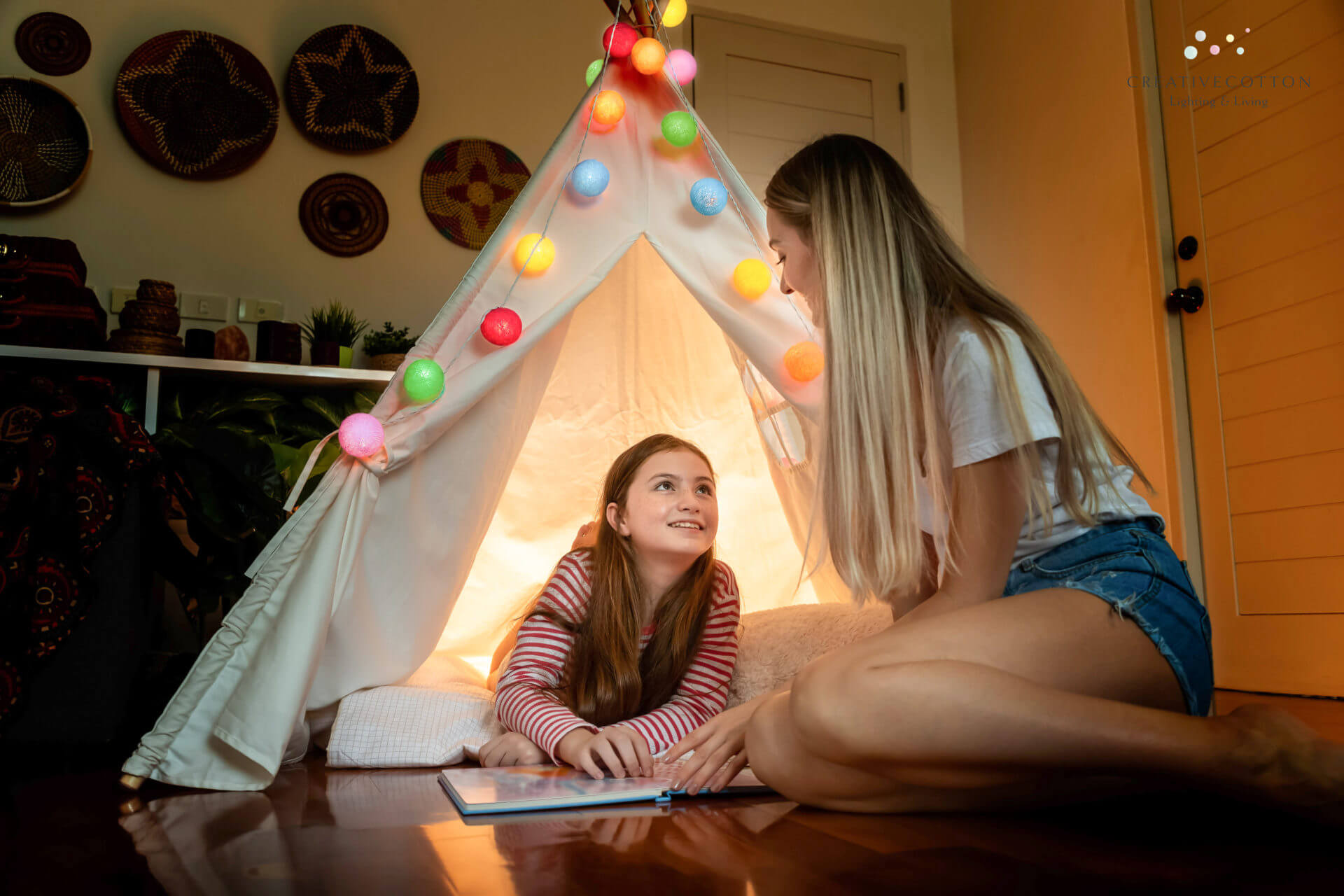 Happy mother with cute daughter reading book inside tepee tent in bedroom enjoy, family relationship concept.