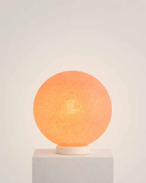 LED Tischlampe mit handgefertigter Baumwollkugel in Orange auf weißem Standfuß; warmweißes LED-Licht setzt einen freundlichen Akzent im Kinderzimmer auf Nachttisch oder Regal.