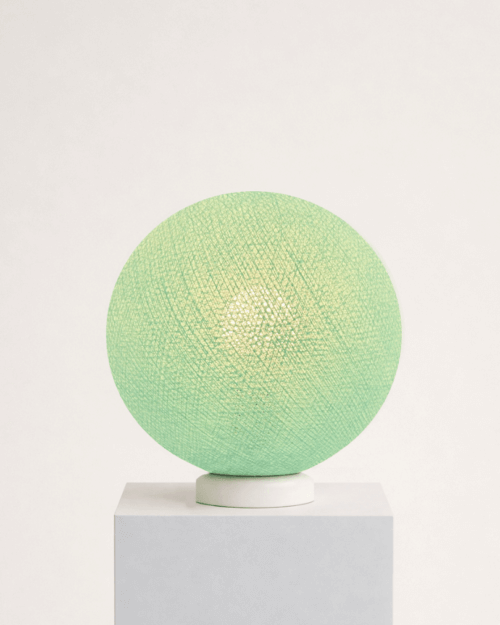 Mintgrüne Tischlampe mit handgearbeiteter Baumwollkugel auf weißem Standfuß; sanftes, warmweißes LED-Nachtlicht auf dem Nachttisch im Kinderzimmer.