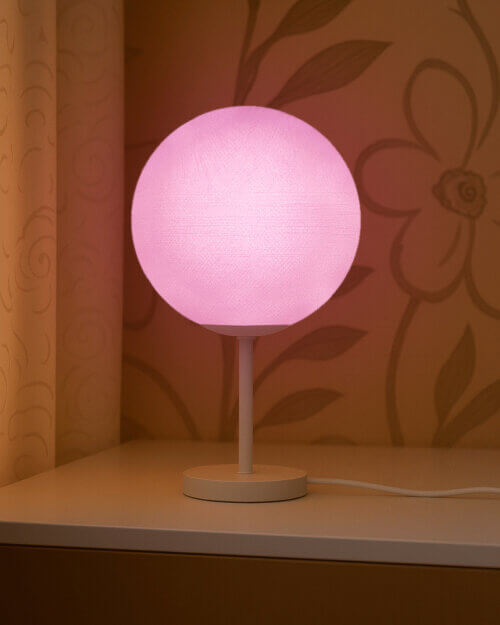 LED Tischlampe mit handgefertigter Baumwollkugel in Violett auf weißem Standfuß; warmweißes Lila LED-Licht schafft eine gemütliche Stimmung im Kinderzimmer.