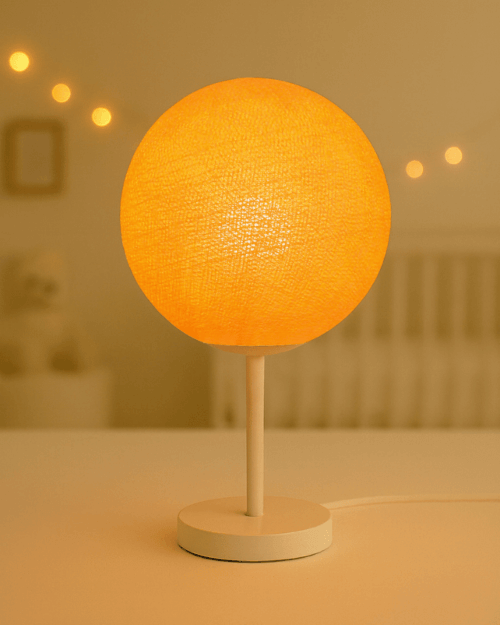 LED Tischlampe mit handgefertigter Baumwollkugel in Orange auf weißem Standfuß; warmweißes LED-Licht setzt einen freundlichen Akzent im Kinderzimmer auf Nachttisch oder Regal.